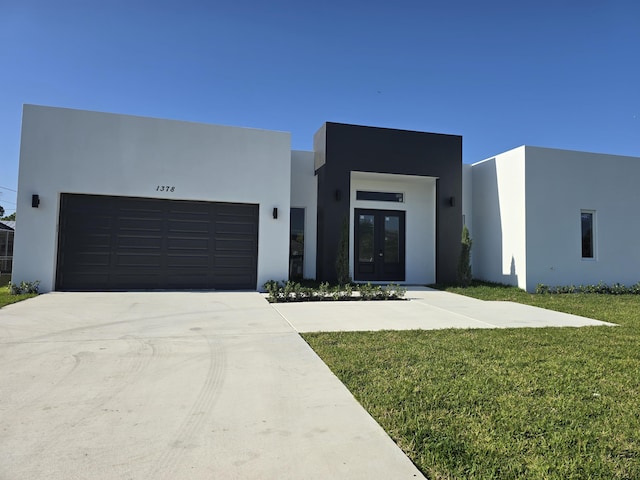 modern home featuring french doors, a garage, driveway, and stucco siding