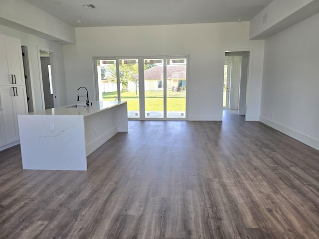 unfurnished living room featuring dark wood finished floors, visible vents, baseboards, and a sink