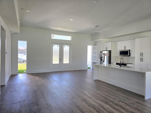 kitchen featuring a center island with sink, a sink, dark wood-style floors, white cabinetry, and appliances with stainless steel finishes