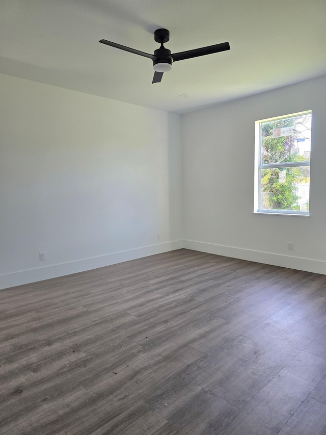 empty room with dark wood-style floors, baseboards, and ceiling fan