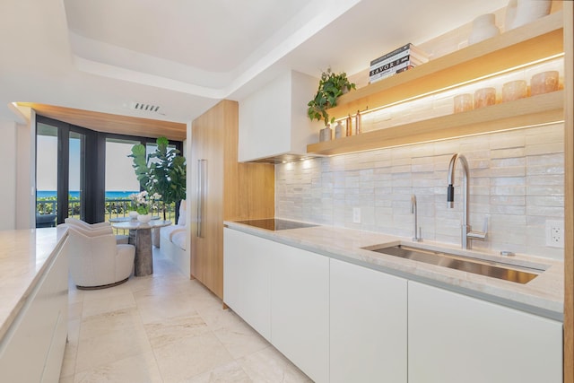 kitchen with visible vents, open shelves, a sink, white cabinets, and light stone countertops