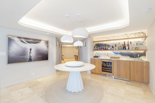 bar with wet bar, a tray ceiling, and beverage cooler