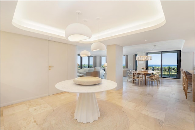 dining room featuring a raised ceiling and baseboards