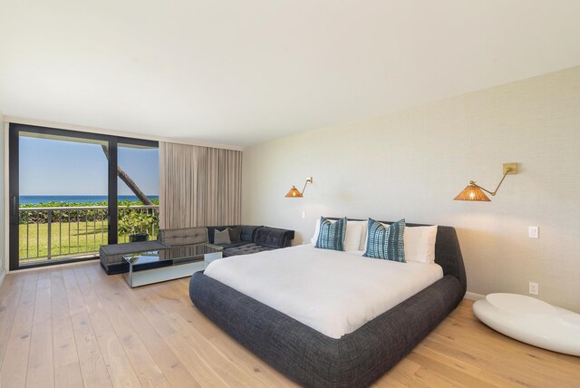 bedroom with wood-type flooring, floor to ceiling windows, and a water view