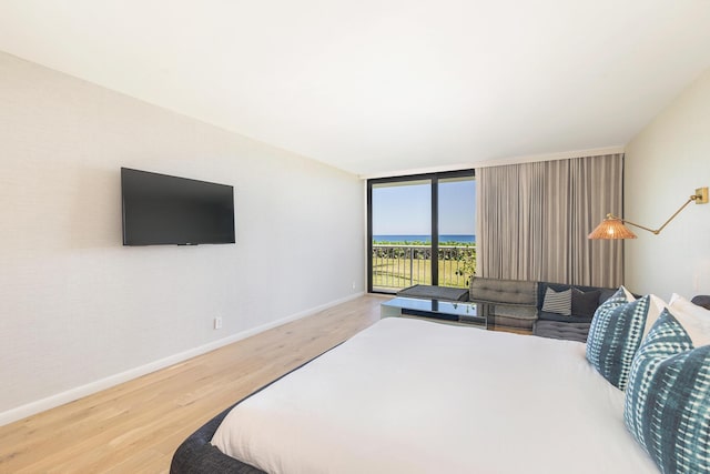 bedroom with access to outside, light wood-style flooring, baseboards, and expansive windows