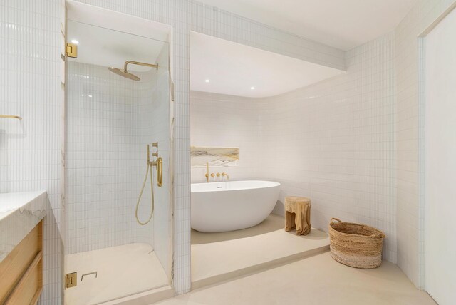 full bath featuring a freestanding bath, tile walls, and a tile shower