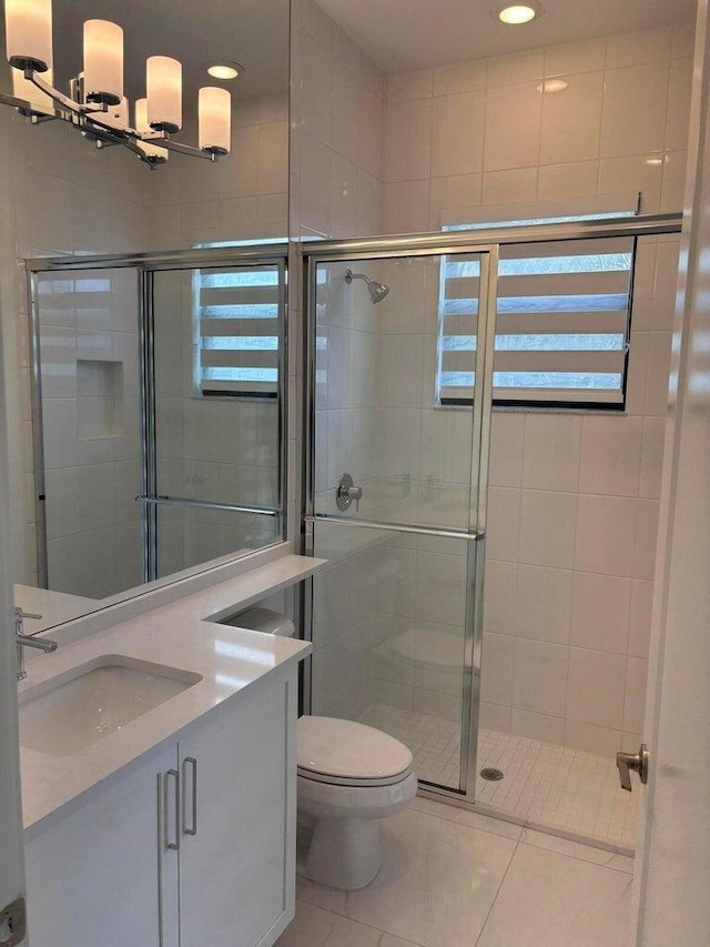 bathroom with a chandelier, toilet, a stall shower, and vanity