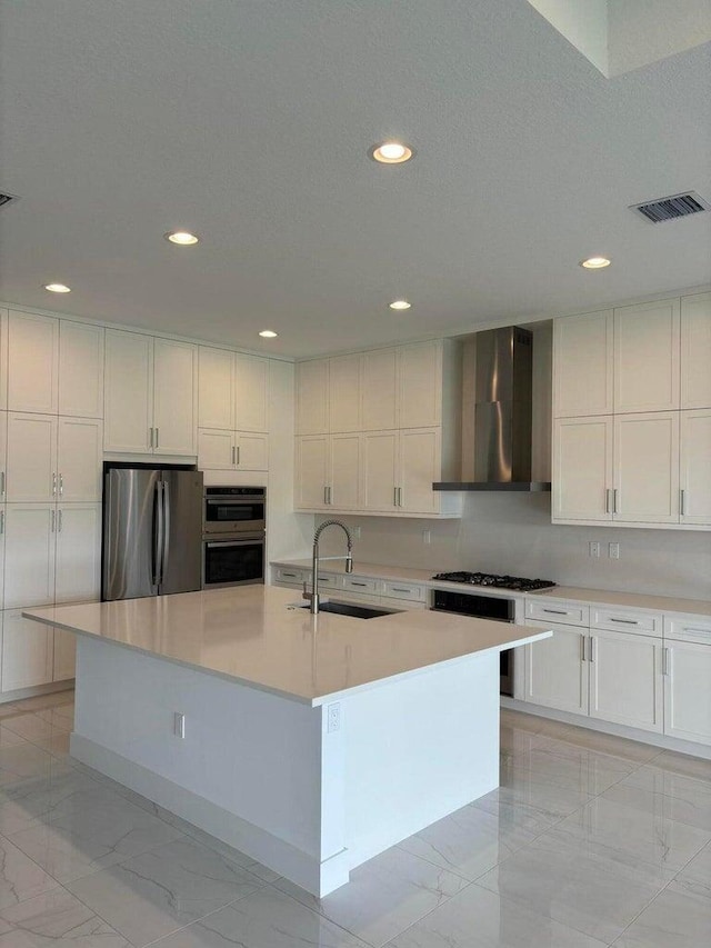 kitchen with visible vents, marble finish floor, a sink, stainless steel appliances, and wall chimney exhaust hood