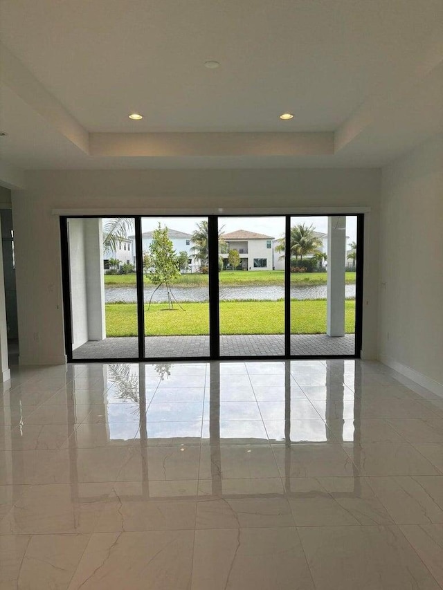 spare room featuring a raised ceiling, plenty of natural light, and marble finish floor