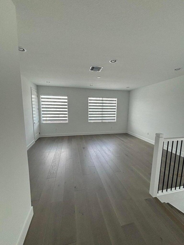 unfurnished room featuring visible vents, dark wood-type flooring, and baseboards