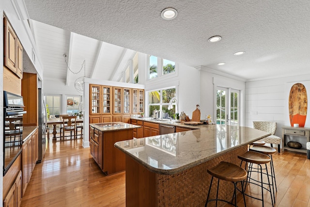 kitchen with brown cabinetry, appliances with stainless steel finishes, a kitchen breakfast bar, light wood-type flooring, and a center island