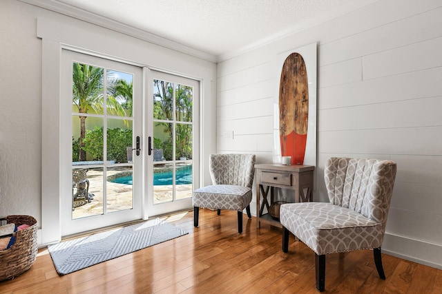 living area with hardwood / wood-style flooring, french doors, a textured wall, and a textured ceiling