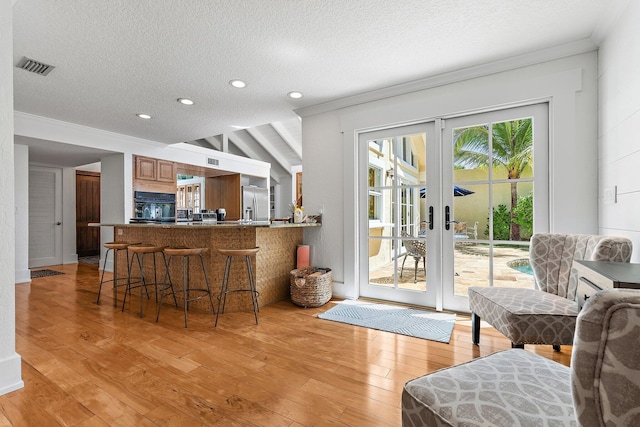 interior space featuring visible vents, ornamental molding, light wood-style floors, french doors, and a textured ceiling