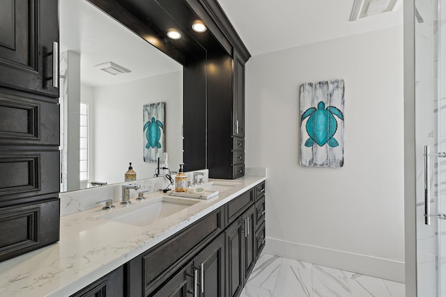 full bathroom featuring double vanity, marble finish floor, baseboards, and a sink