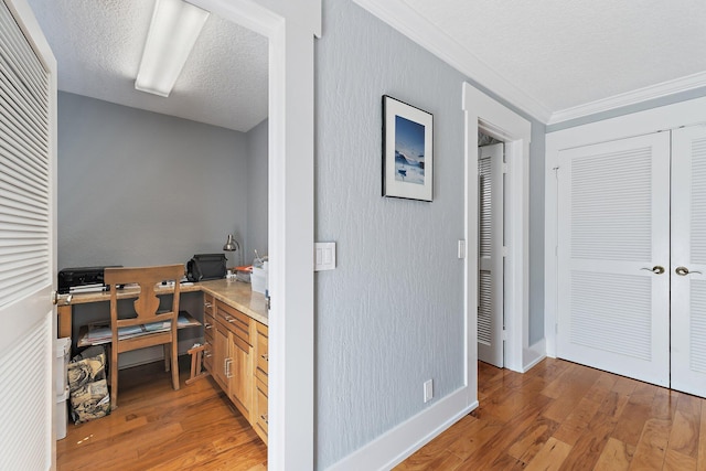 office area featuring baseboards, light wood-style floors, crown molding, and a textured ceiling