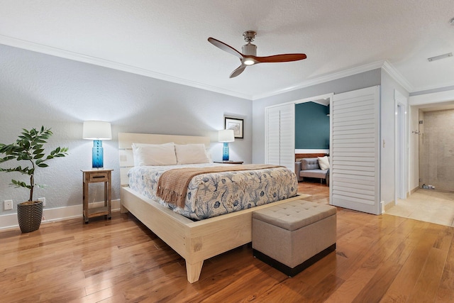 bedroom with light wood finished floors, visible vents, baseboards, ornamental molding, and a ceiling fan