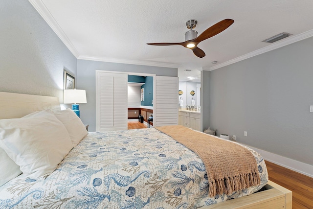 bedroom with visible vents, ornamental molding, a ceiling fan, wood finished floors, and baseboards