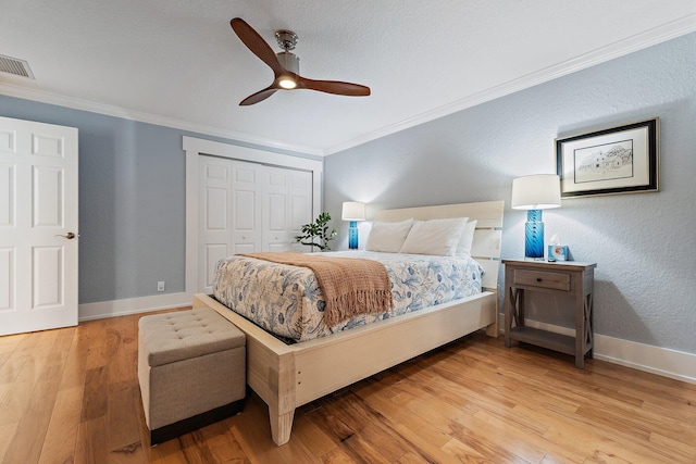 bedroom with baseboards, visible vents, ornamental molding, light wood-style floors, and a closet