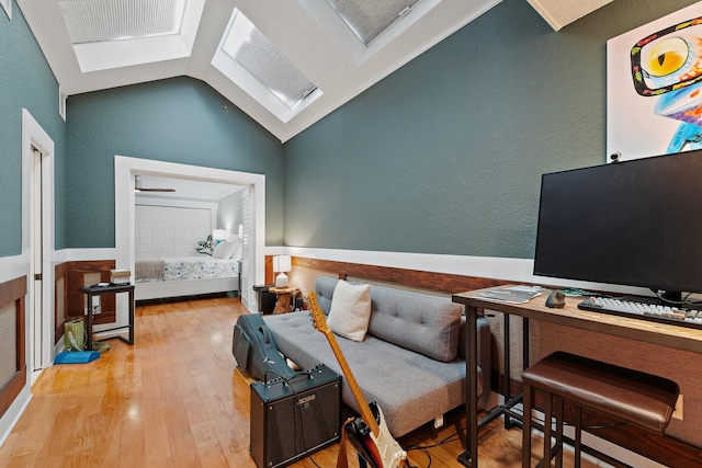 living area featuring vaulted ceiling, a textured wall, and light wood-type flooring