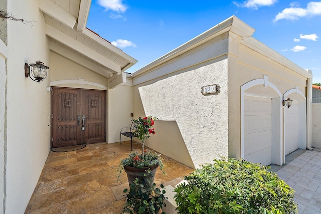 property entrance featuring a garage and stucco siding