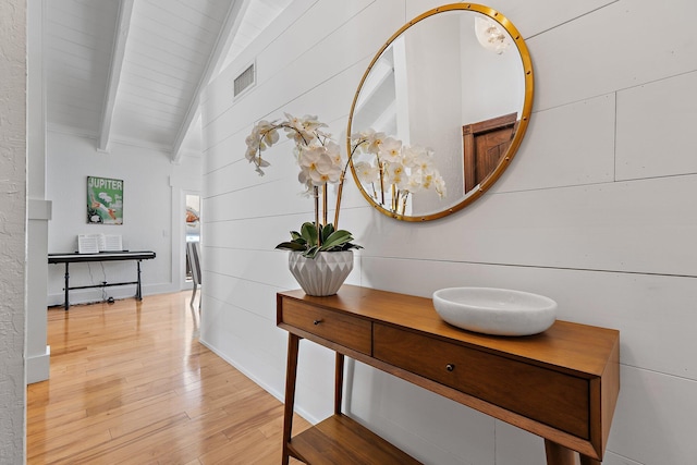 room details featuring visible vents, beamed ceiling, and wood finished floors