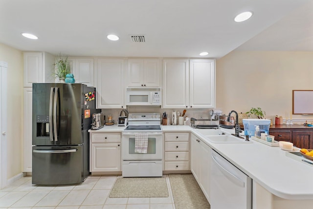 kitchen featuring light tile patterned floors, white cabinets, white appliances, and a sink