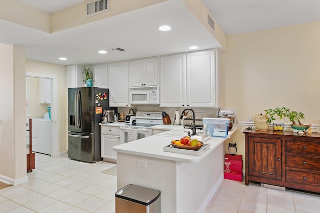 kitchen featuring visible vents, light countertops, a peninsula, white appliances, and a sink