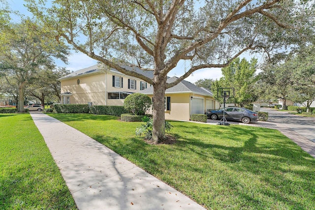 traditional-style home with a garage, driveway, a front lawn, and stucco siding