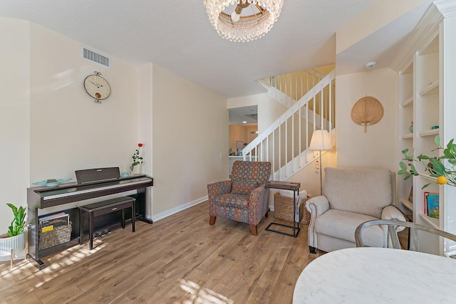 sitting room with baseboards, stairway, an inviting chandelier, wood finished floors, and a textured ceiling