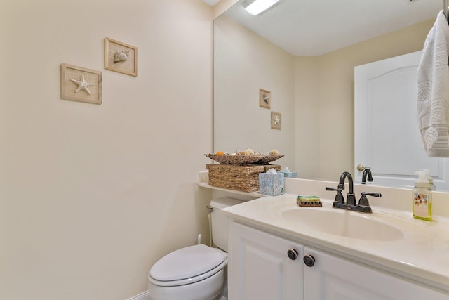 half bath with toilet, vanity, and baseboards