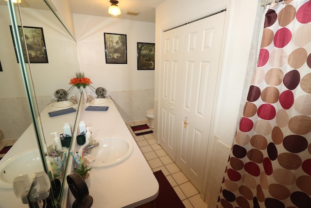 full bath featuring visible vents, double vanity, a sink, tile patterned flooring, and toilet