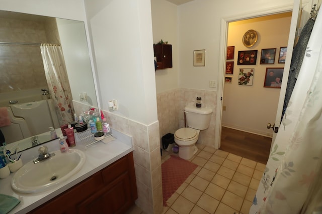 full bath with a wainscoted wall, toilet, tile walls, tile patterned flooring, and vanity