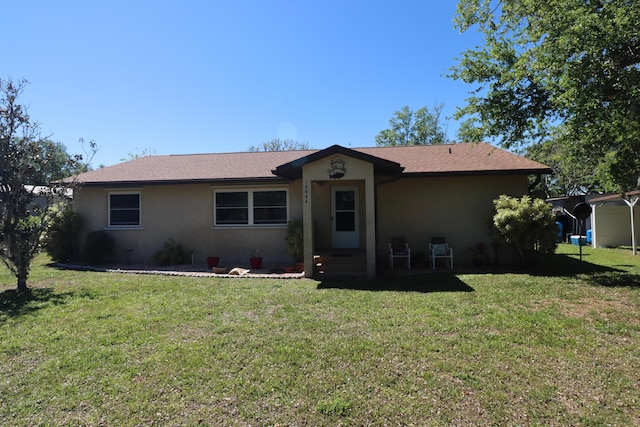 ranch-style house featuring a front lawn, roof with shingles, and stucco siding