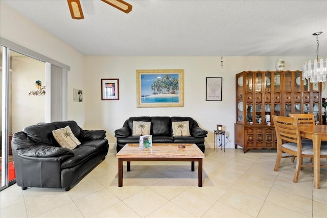living room with a textured ceiling, light tile patterned flooring, and ceiling fan with notable chandelier