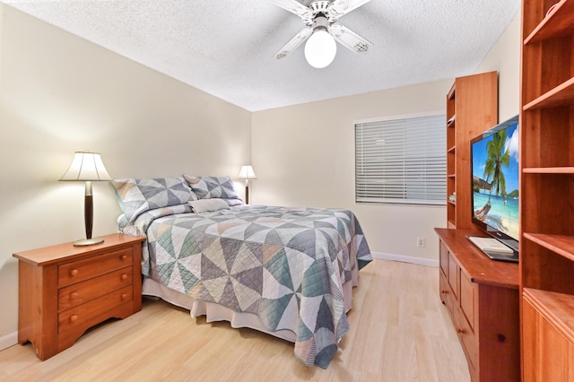 bedroom with a textured ceiling, light wood-type flooring, baseboards, and a ceiling fan