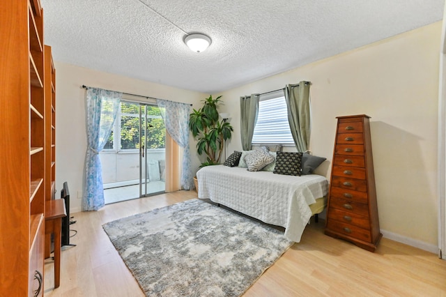 bedroom featuring access to exterior, multiple windows, and light wood-style flooring