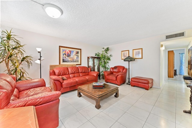 living room with light tile patterned floors, visible vents, and a textured ceiling