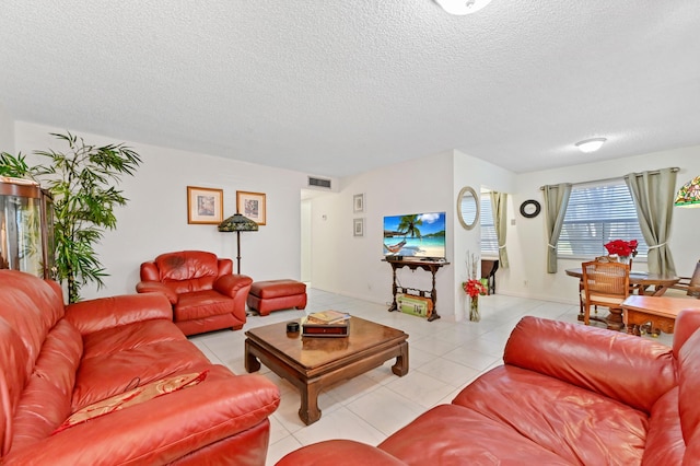 living room featuring light tile patterned floors, visible vents, and a textured ceiling