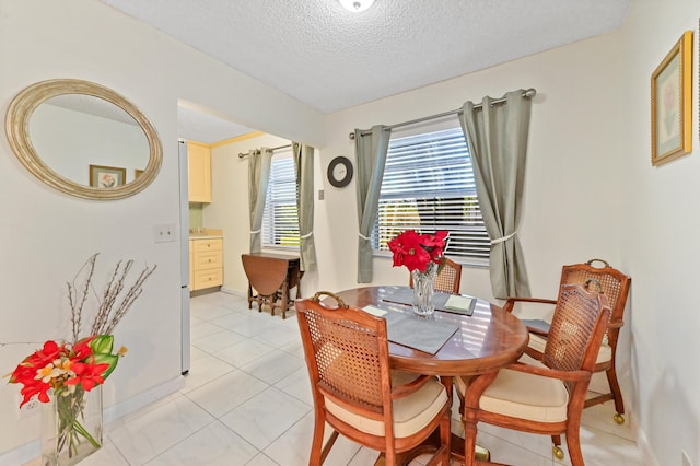 dining area featuring light tile patterned floors and a textured ceiling