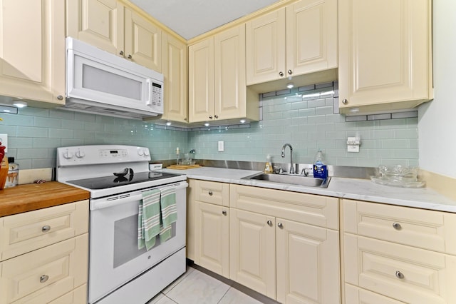 kitchen featuring a sink, cream cabinets, white appliances, light countertops, and decorative backsplash