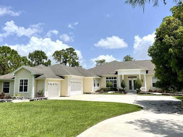 view of front of property with french doors, an attached garage, driveway, and a front lawn