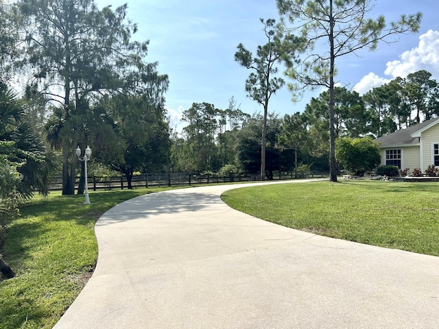 view of property's community with a lawn and fence