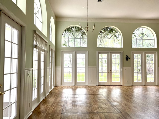 interior space featuring french doors, a notable chandelier, dark wood finished floors, and wainscoting