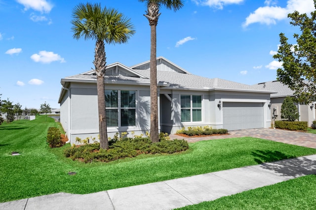 ranch-style house featuring roof with shingles, an attached garage, stucco siding, a front lawn, and decorative driveway