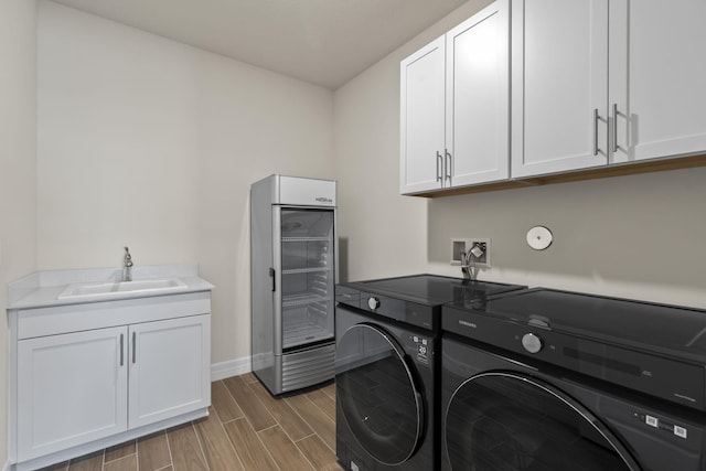 laundry room featuring wood finish floors, independent washer and dryer, a sink, wine cooler, and cabinet space