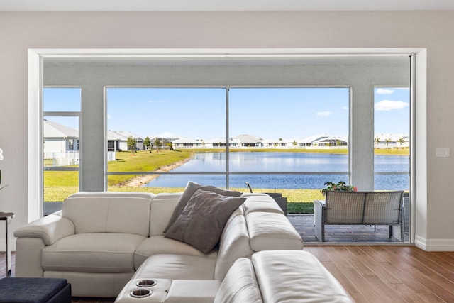 living area with wood finished floors, a water view, a residential view, and baseboards