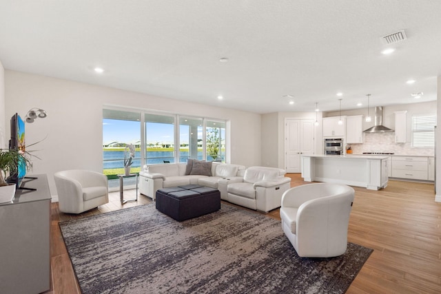 living room with visible vents, recessed lighting, light wood-type flooring, and a water view