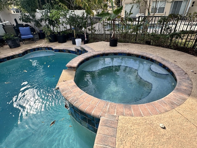 view of pool featuring fence and a pool with connected hot tub