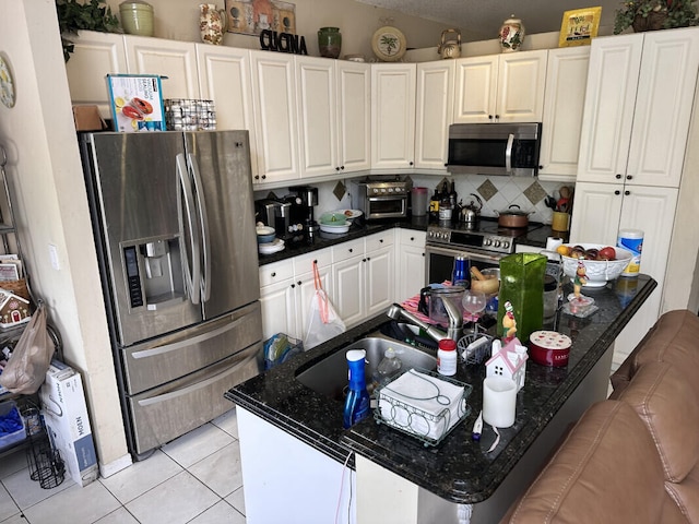 kitchen with backsplash, dark countertops, light tile patterned flooring, and appliances with stainless steel finishes