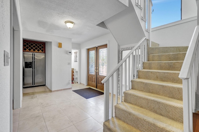 entrance foyer with stairway, light tile patterned floors, baseboards, and a textured ceiling